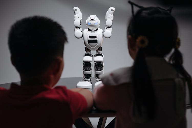 Kids Looking At White Toy Robot On The Table