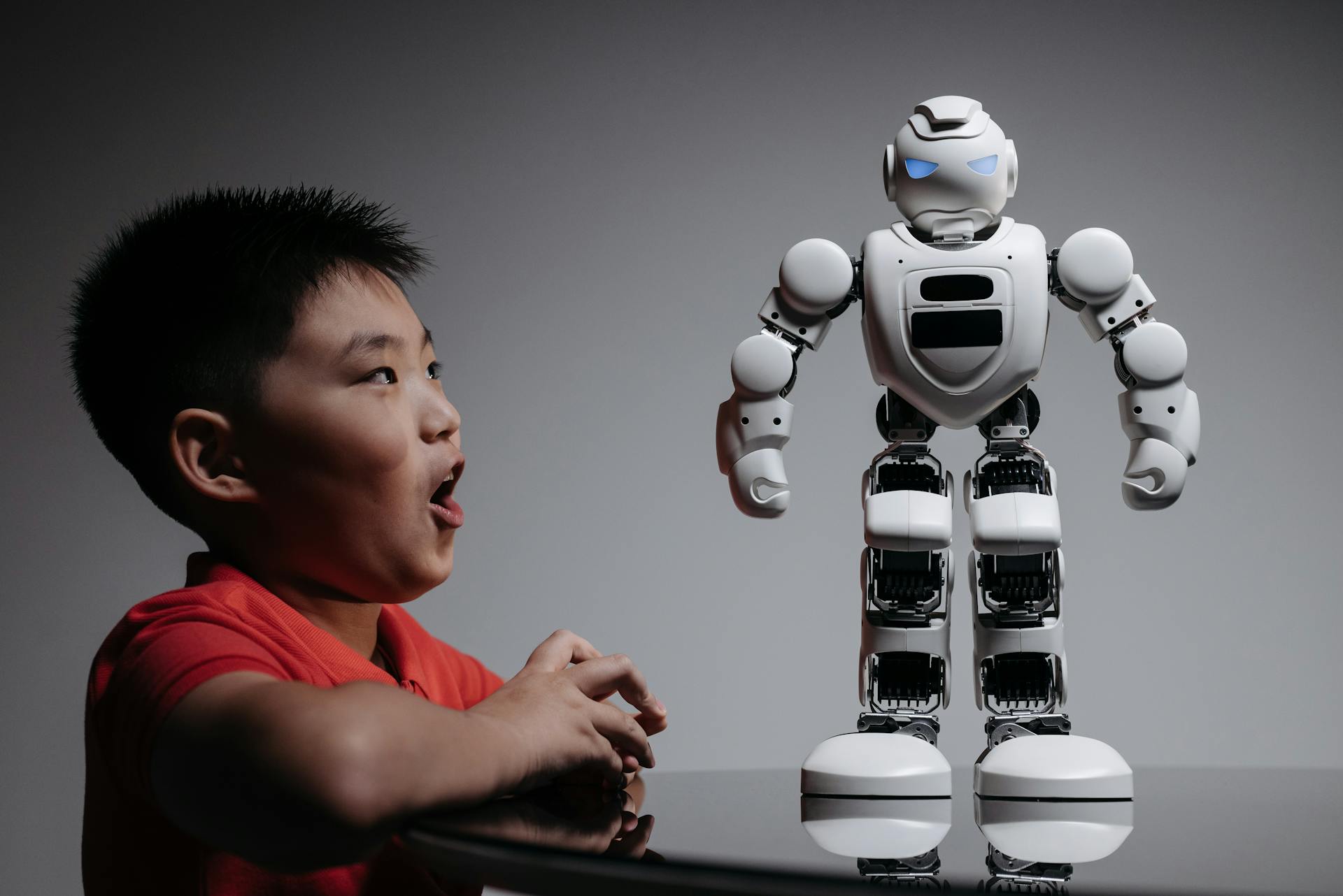 A Boy Looking at the White Toy Robot