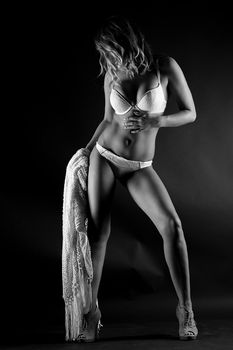 Stylish black and white photo of a woman in lingerie posing elegantly in a studio setting.
