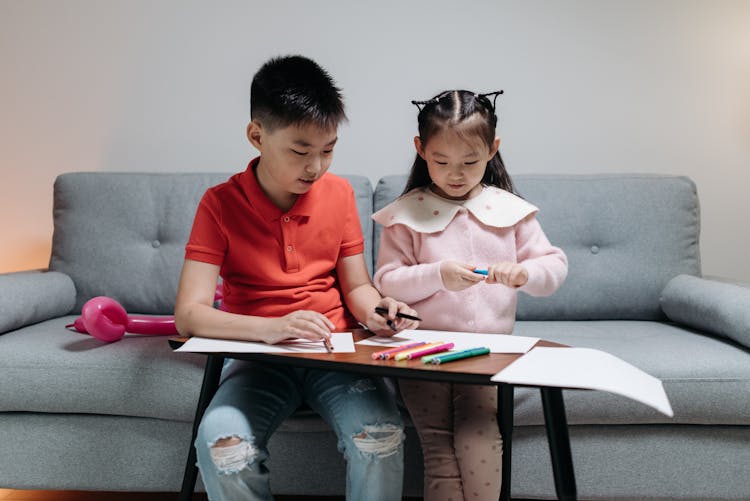 Kids Sitting On A Couch Holding Coloring Materials