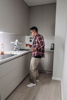 An Asian man in a plaid shirt plays with a toy robot in a sleek, modern kitchen setting.