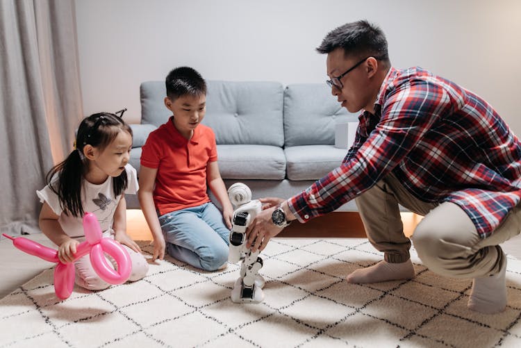 Man Playing Toy Robot With A Boy And Girl