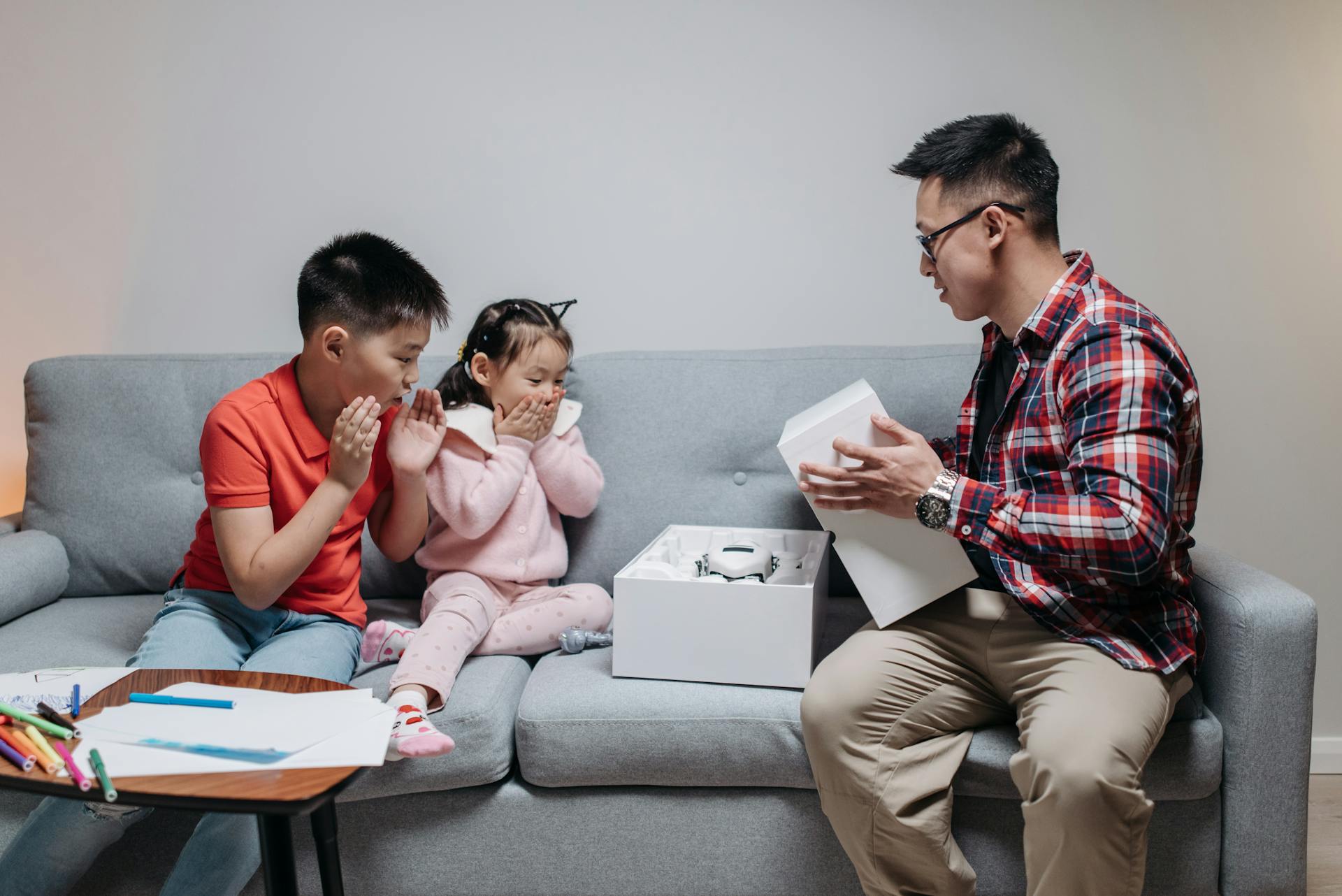 A family of three express surprise while unboxing a cutting-edge robot toy.