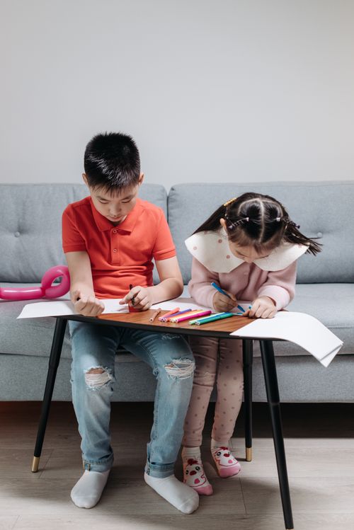 Free Two siblings drawing with colored pens in a cozy living room setting. Stock Photo