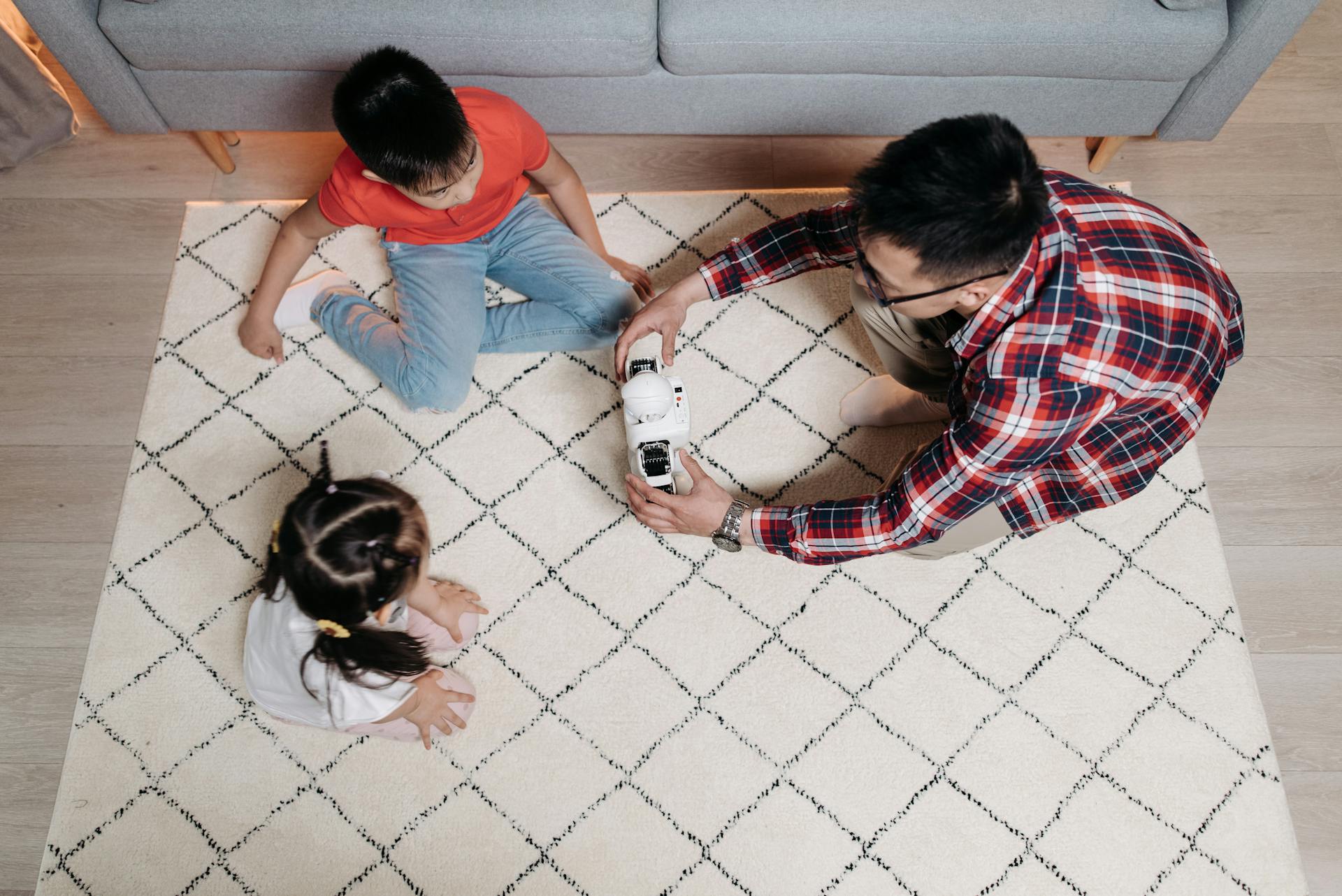 A father and his two children enjoying playtime with a toy robot in the living room.