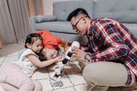 Family bonding time with a father and kids playing creatively with a robot toy.