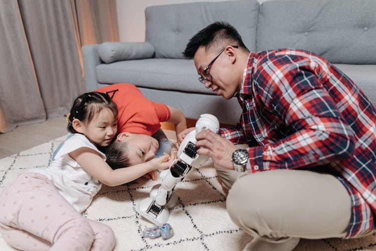 Father And Children Enjoying The Robot They Are Playing