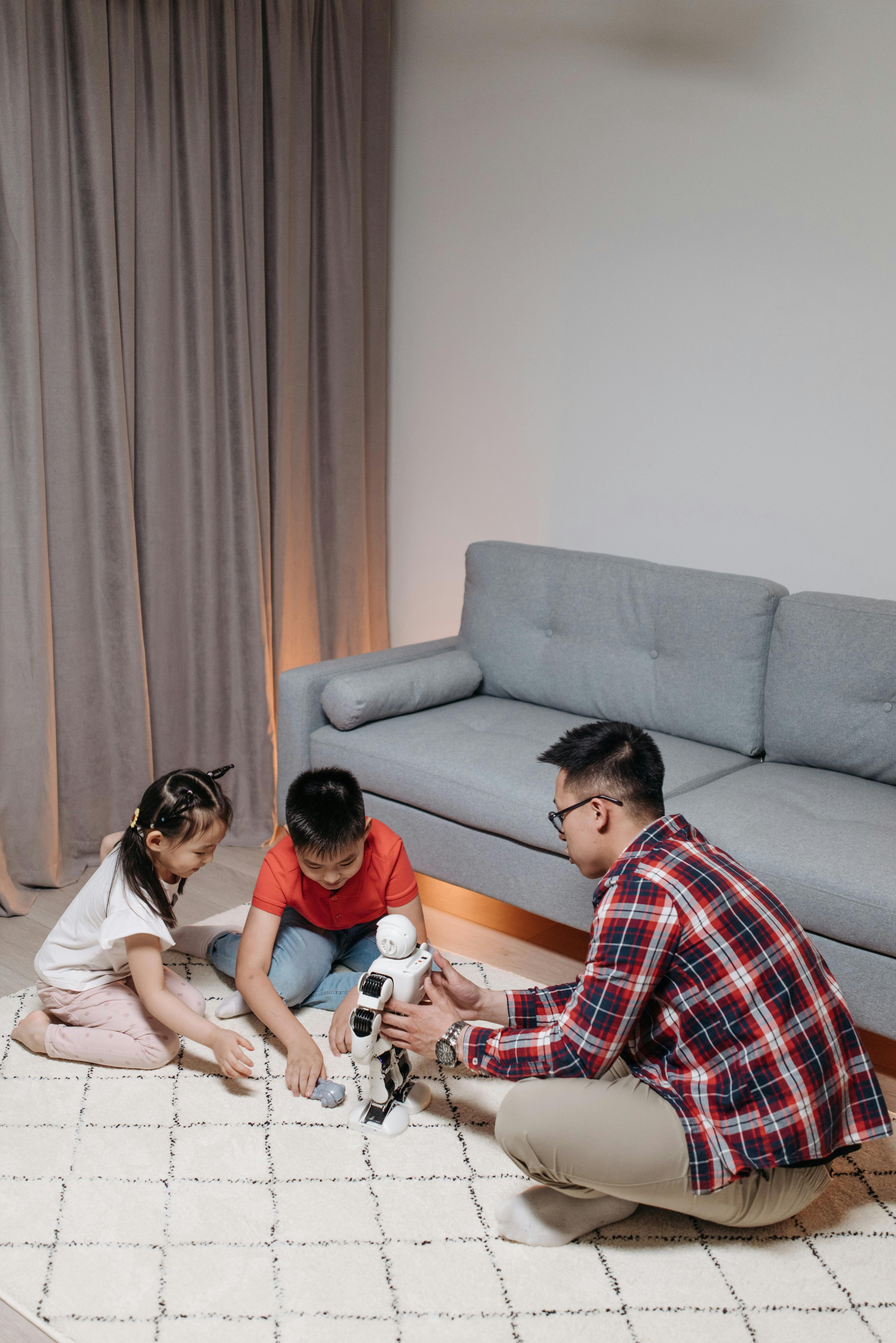 a man playing with his kids while holding the robot