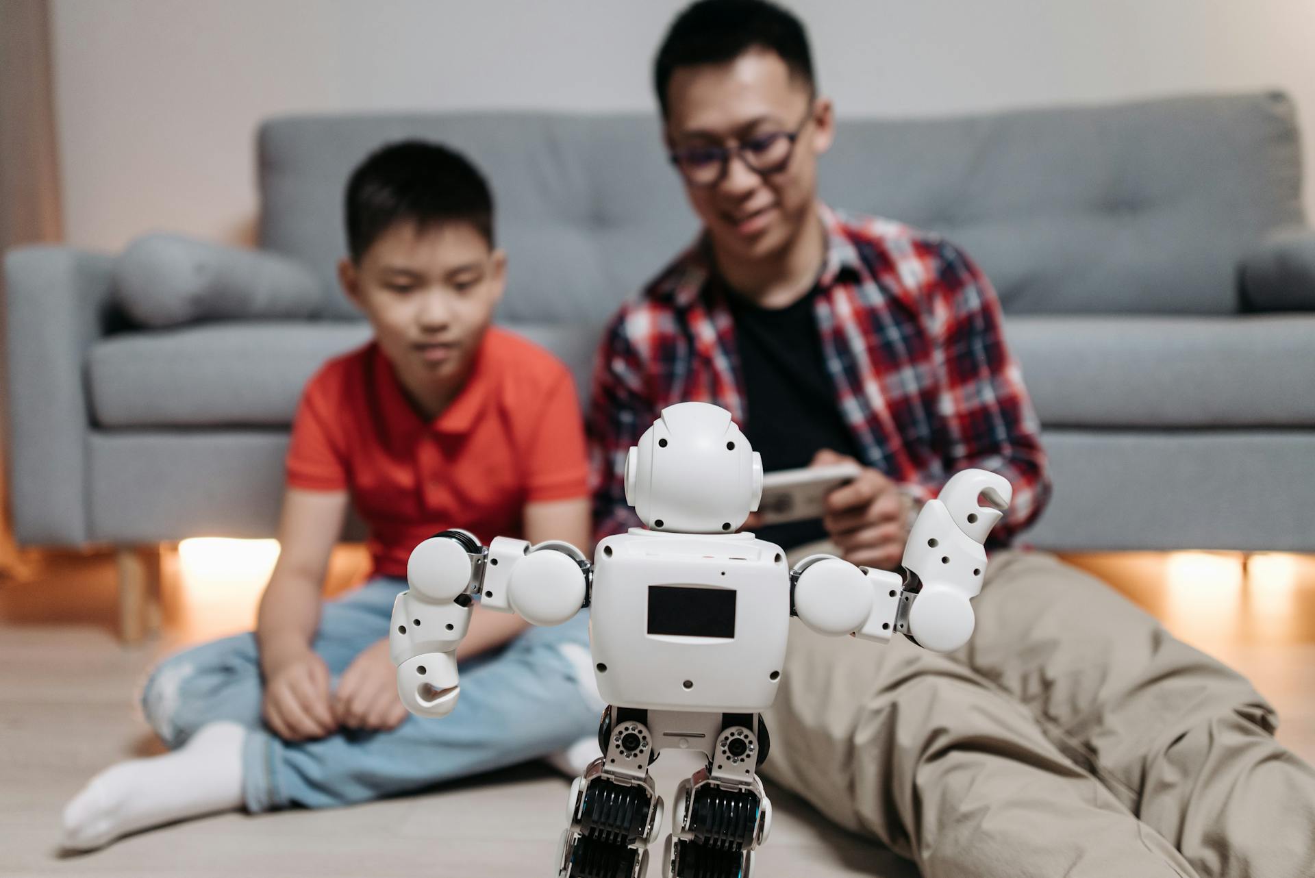 Father and son bonding while playing with a modern robot toy in their living room.