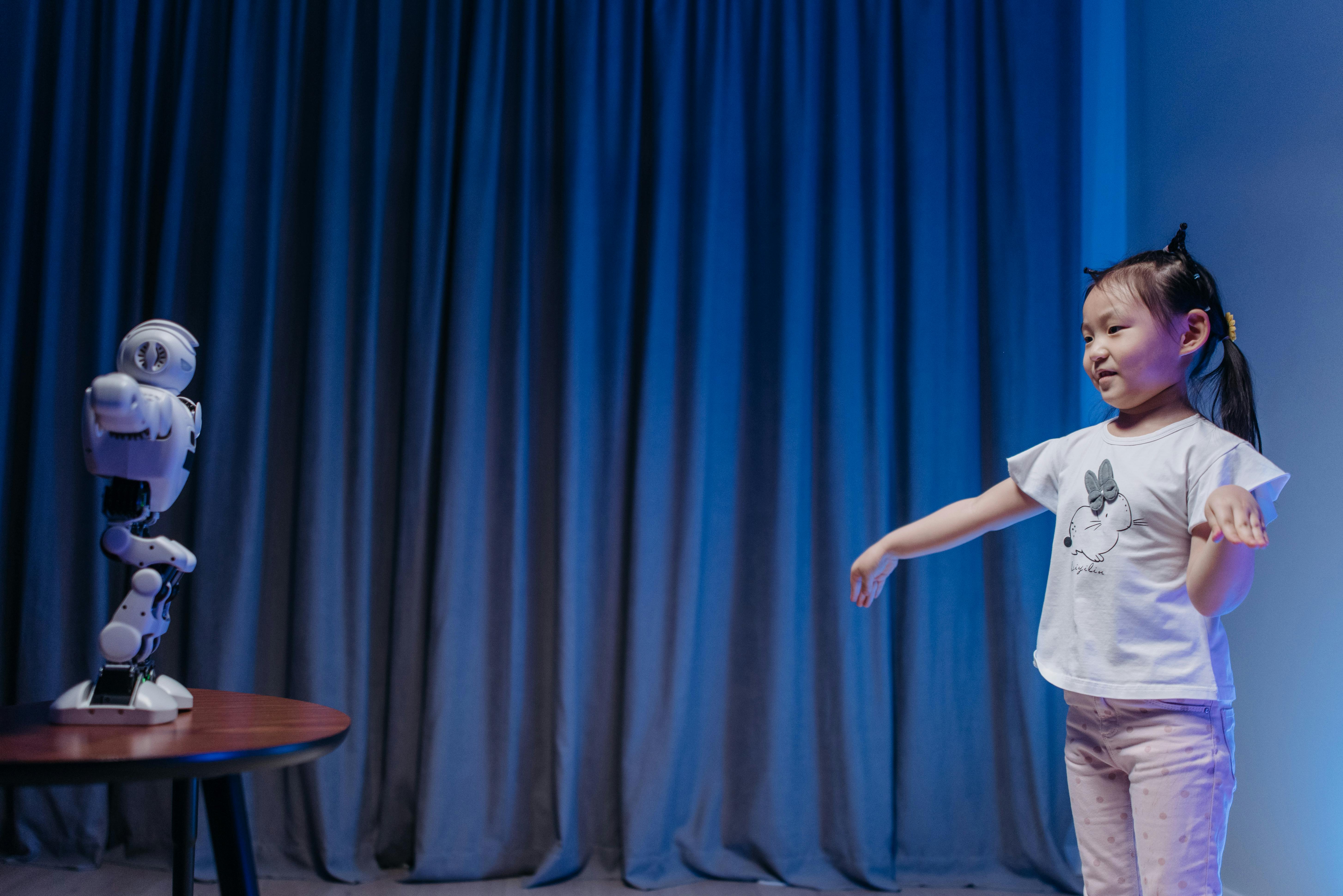 a child facing a toy robot standing on a wooden table