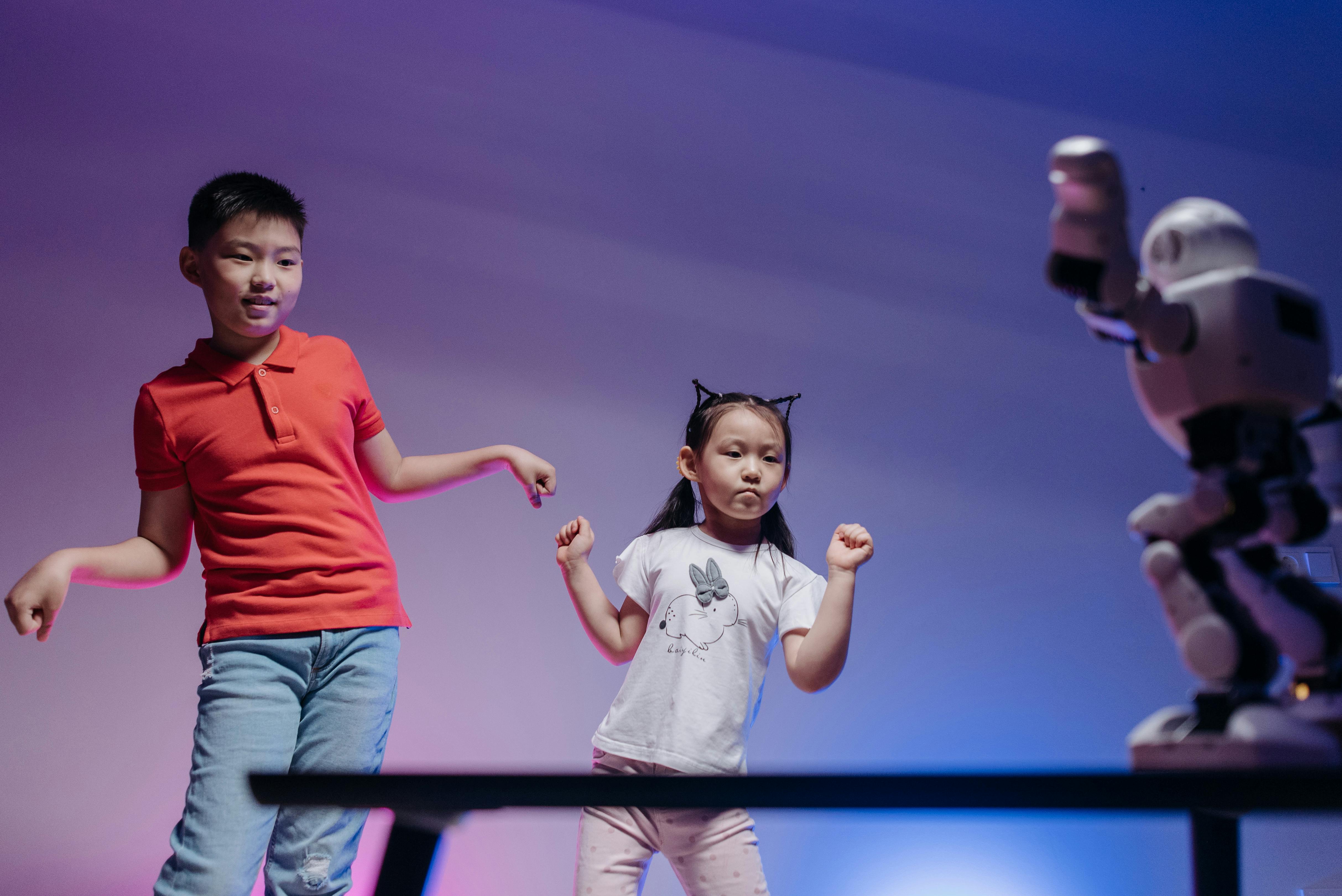 a low angle shot of kids dancing with the robot