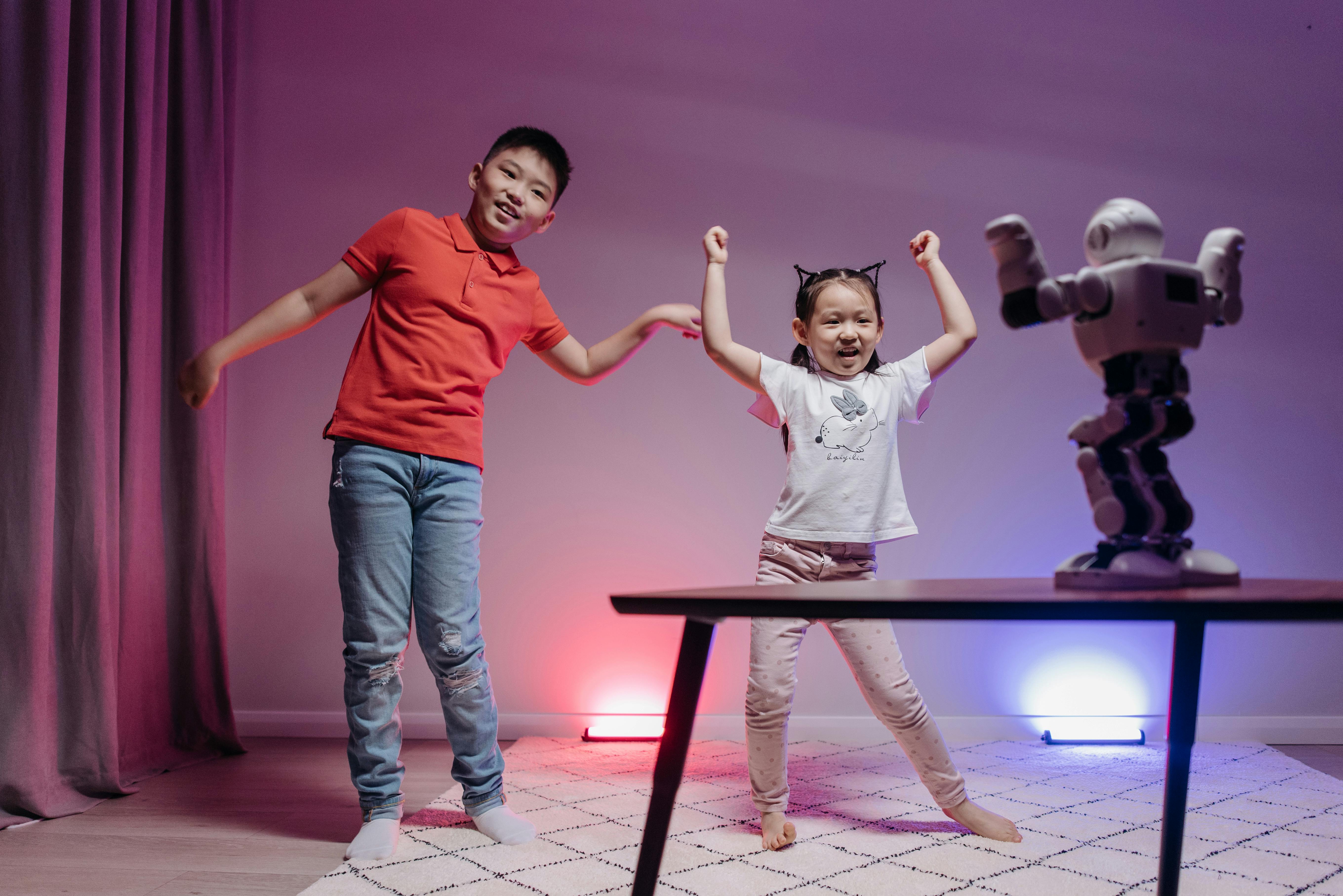 kids dancing in front of the robot on the table