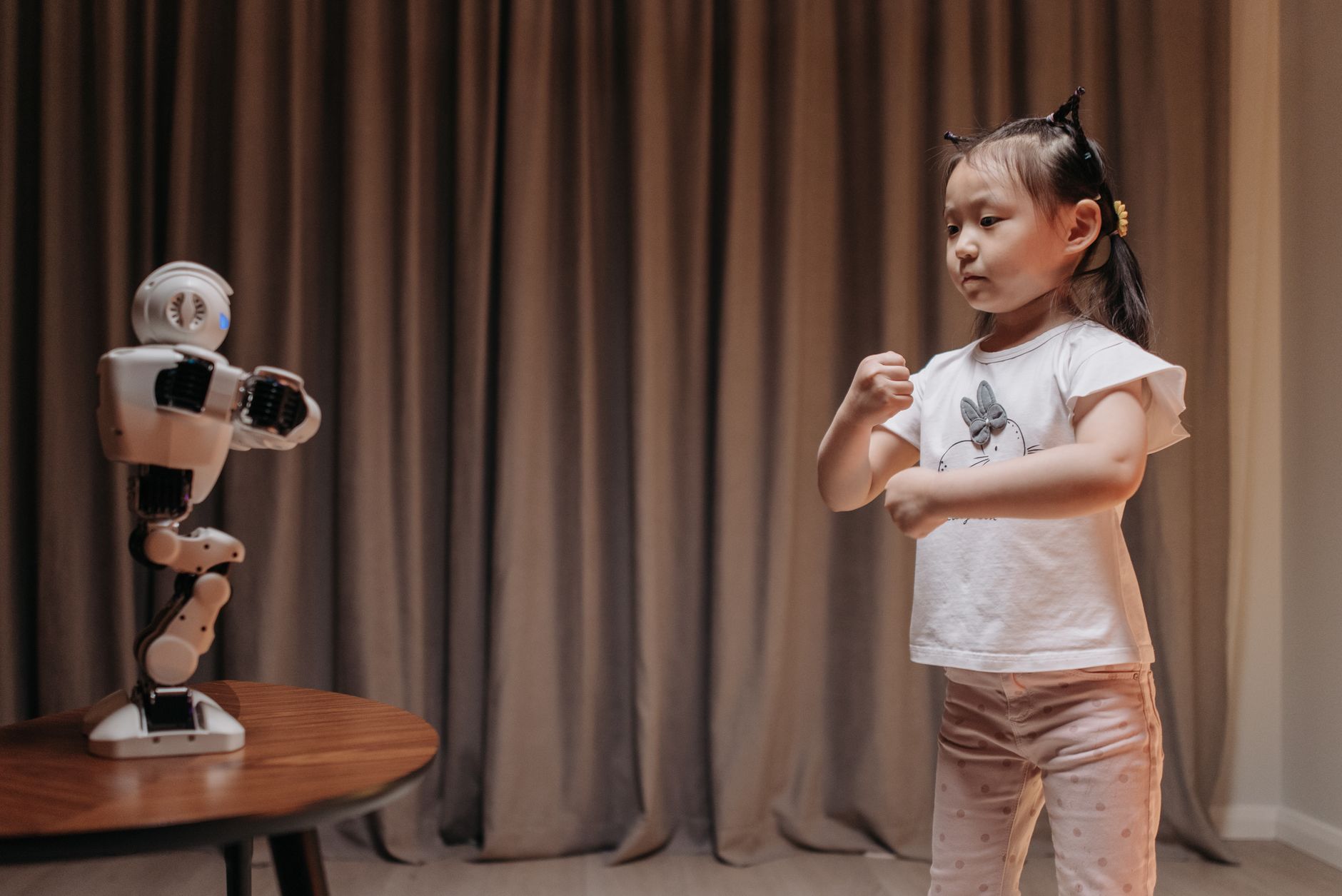 Child playfully imitates a robot in an indoor setting, showcasing creativity and fun interaction with technology.