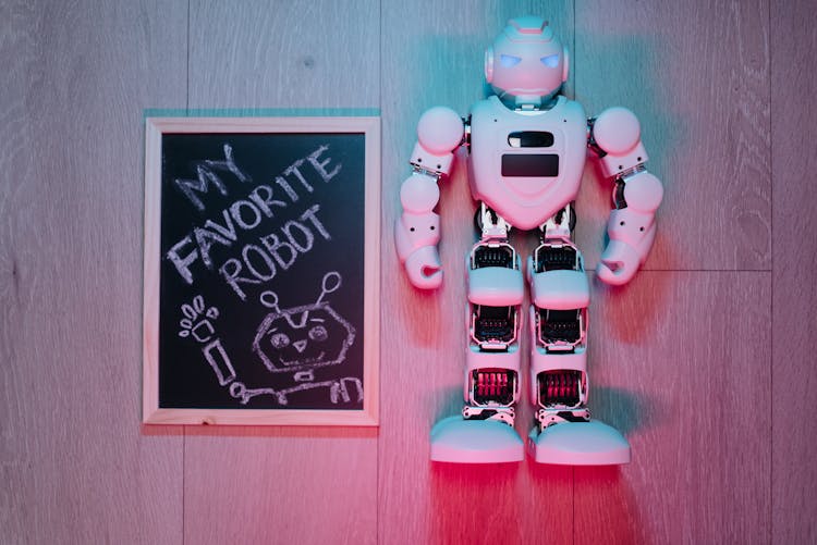 White Robot On A Wooden Surface Beside A Board