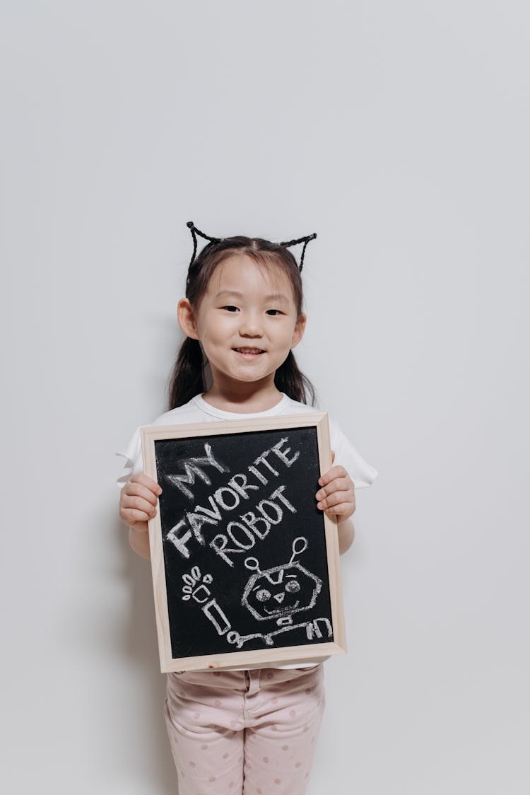 A Cute Little Girl Holding A Wooden Board