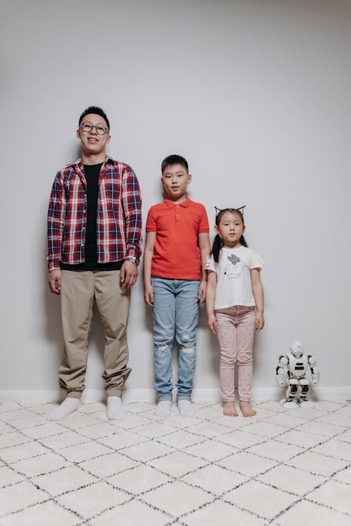 Free A Father with His Kids Leaning on the Wall with the Robot Stock Photo