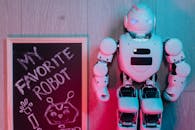 Close-up Shot of a Board Beside a Robot on the Wooden Flooring