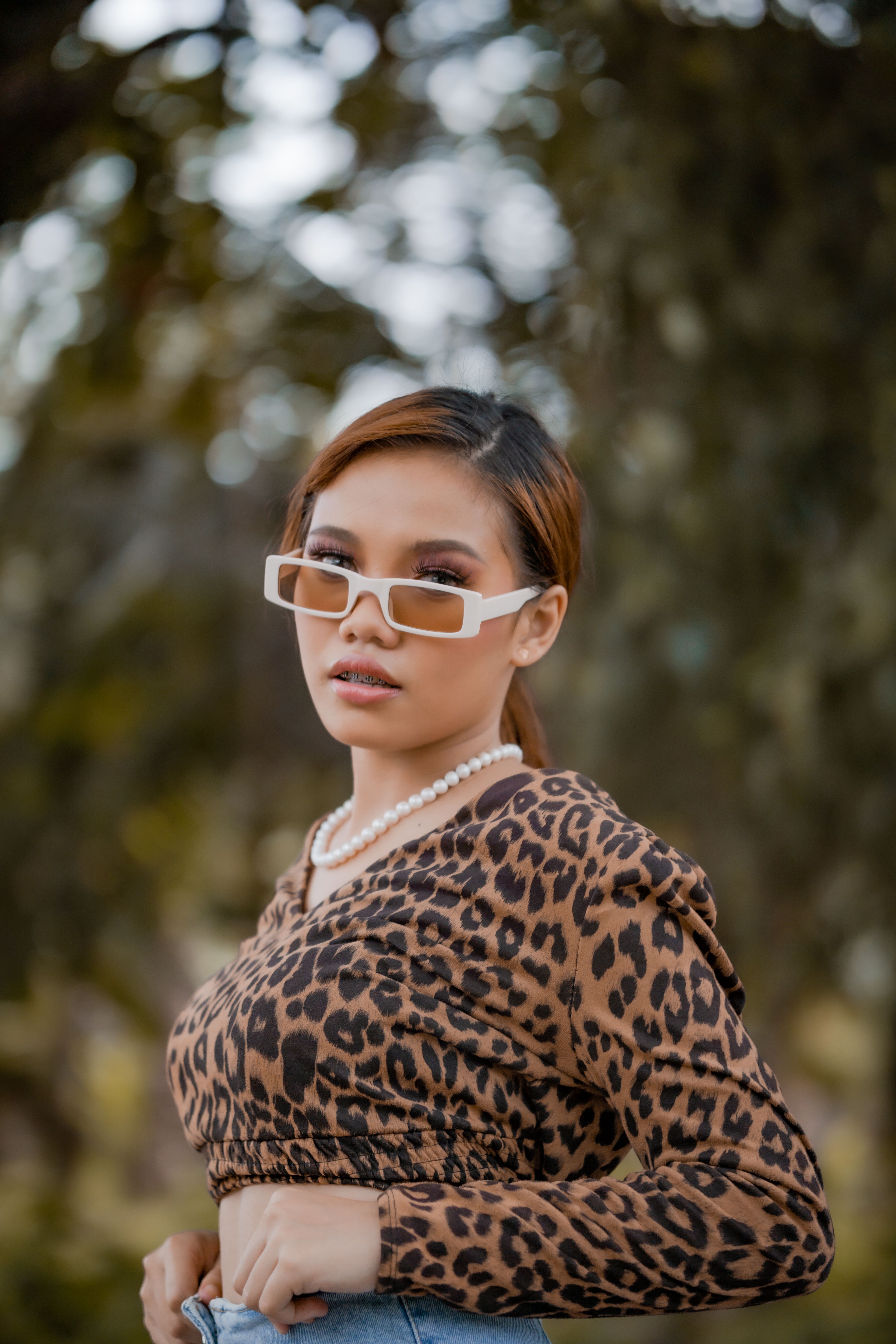 Fashionable woman outdoors wearing leopard print blouse and sunglasses. Modern style in nature.