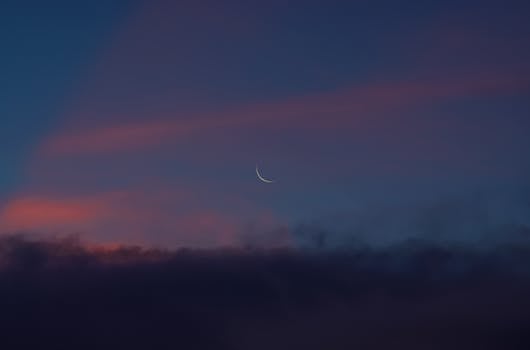 Crescent moon in a serene twilight sky with colorful clouds in Malita, Philippines.