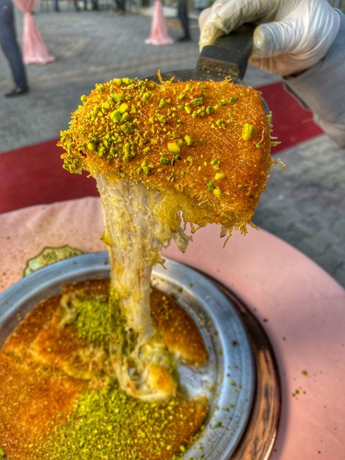Free Delicious traditional Turkish knafeh served hot with pistachios in Kâhta, Turkey. Stock Photo