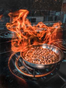 A frying pan of pistachios on fire, capturing the intense flames on a kitchen stove.