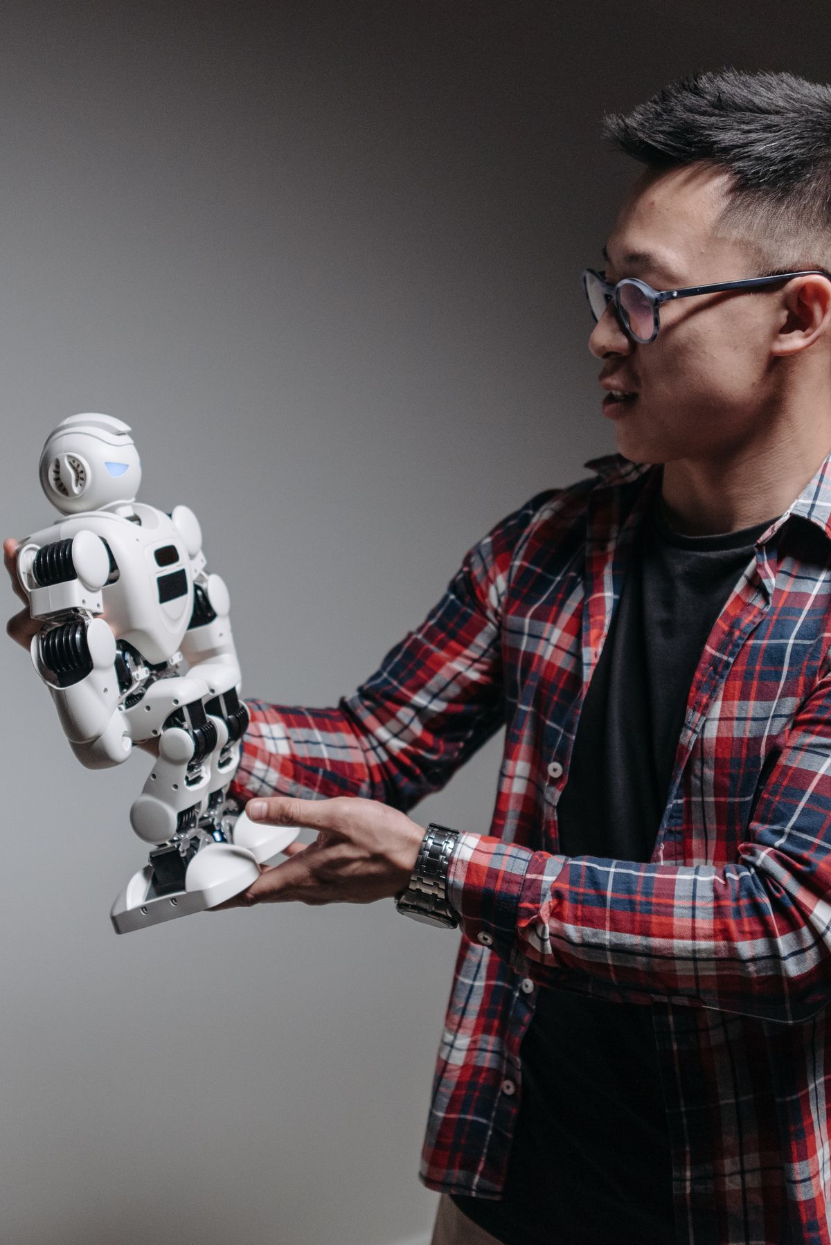 Man examining a humanoid robot, representing hands-on exploration of AI tools and prompting