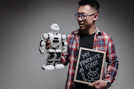 Asian man holding a robot and chalkboard with 'My Favorite Robot' written on it.