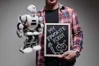 A Person Wearing Plaid Long Sleeves Holding a Wooden Board and Robot