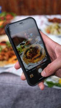 Close-up of a person photographing food with a smartphone at a restaurant.