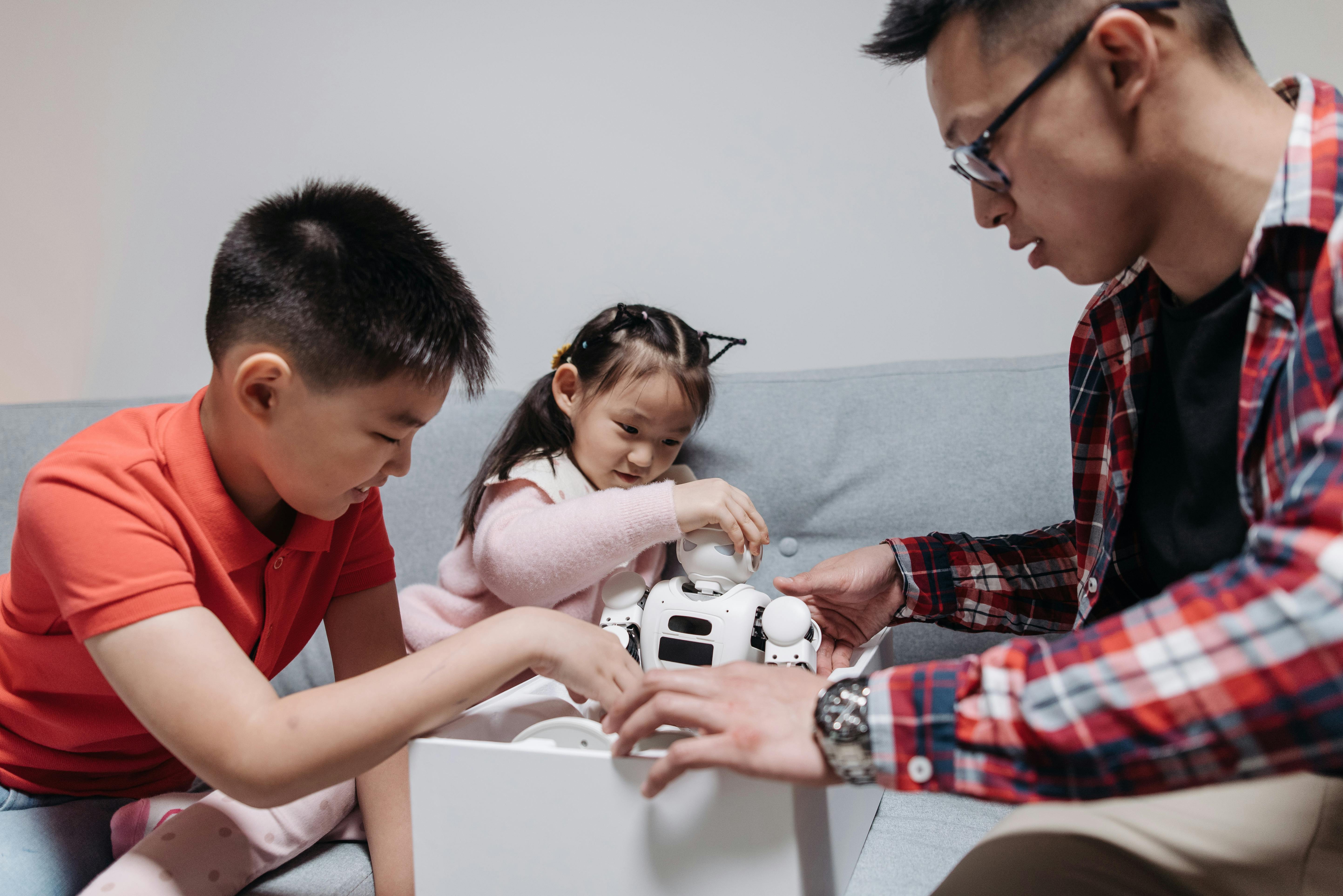 a man with two children unboxing a toy robot