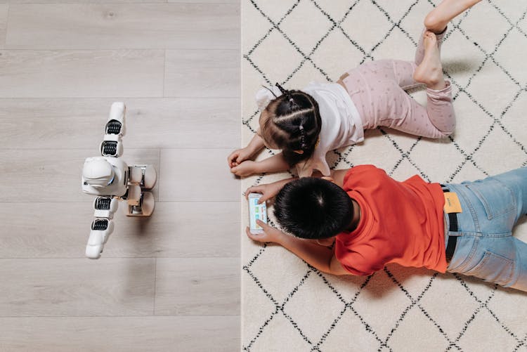 Kids Lying On The Carpet In Front Of A Robot