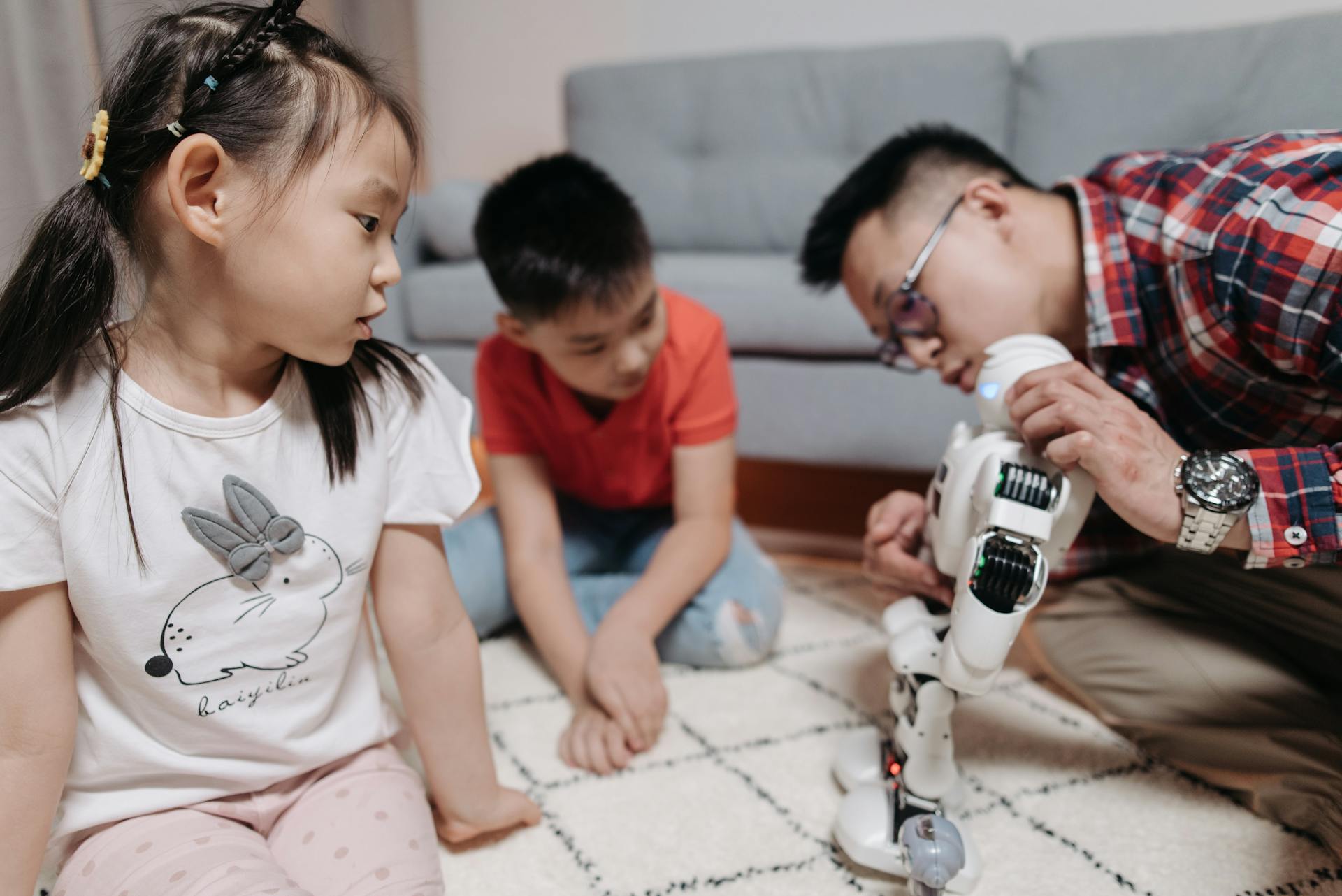 Father and children enjoying creative playtime with a robot indoors.