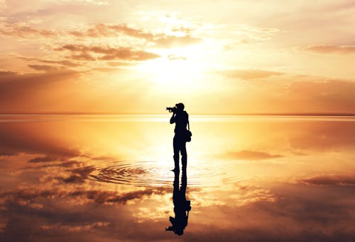 Silhouette of Man Standing on the Seashore during Sunset