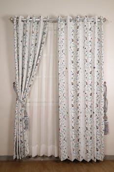 Elegant floral patterned curtains with sheer fabric on a white wall, perfect for minimalist interiors.