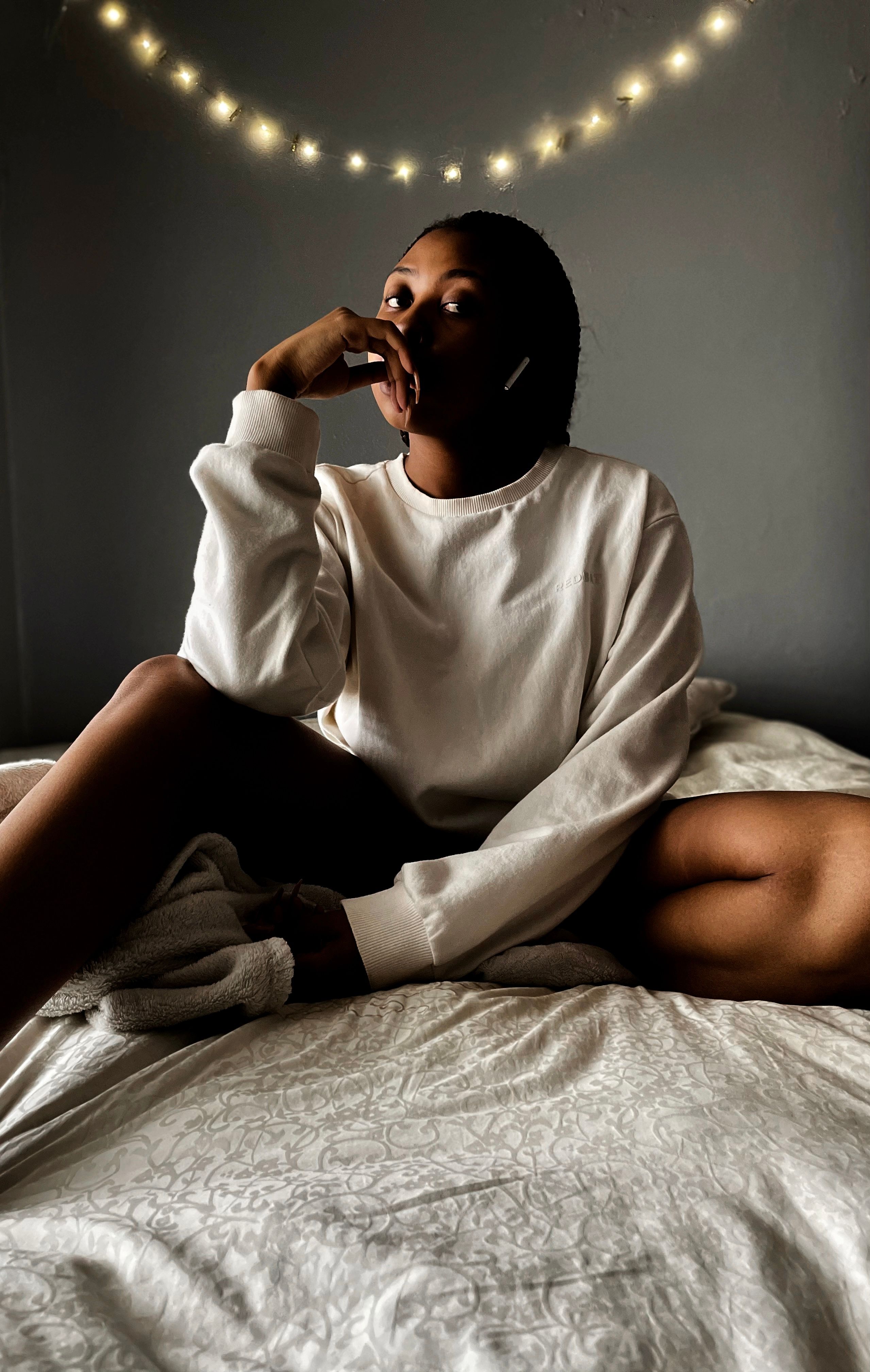 Woman in White Sweater Sitting on Her Bed · Free Stock Photo