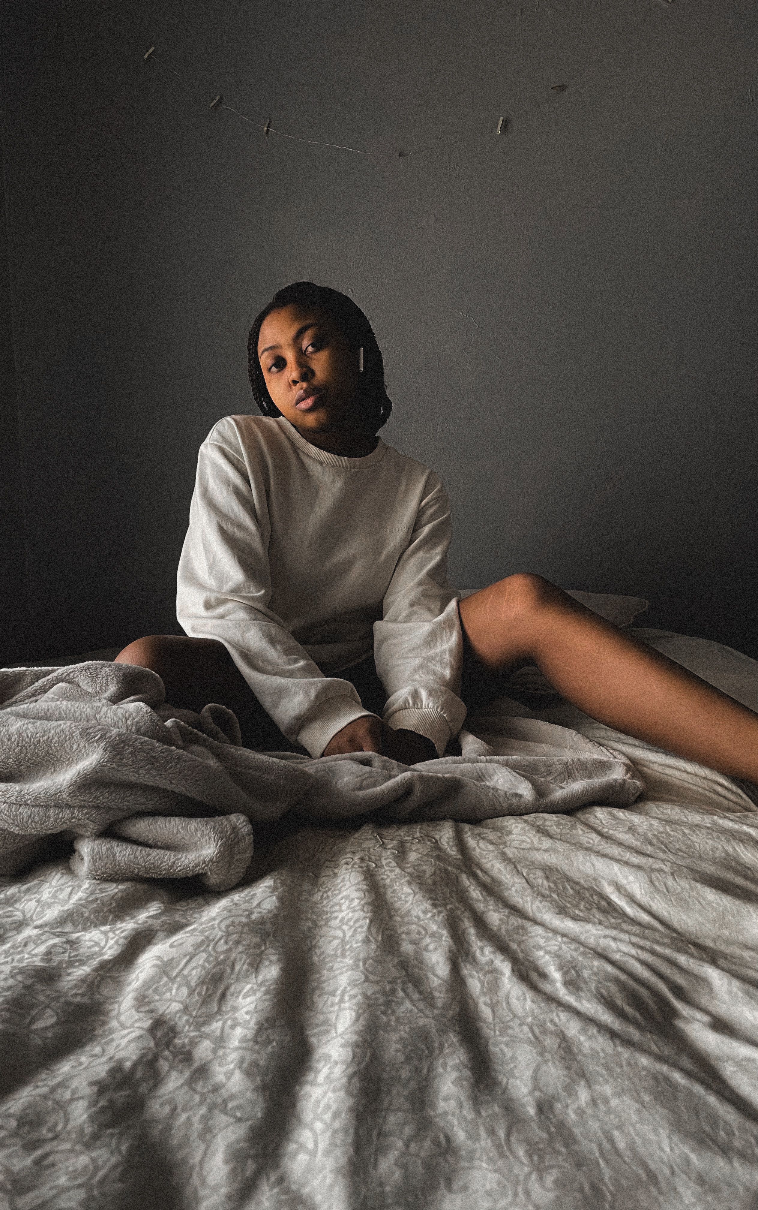 Woman in White Sweater Sitting on Her Bed · Free Stock Photo