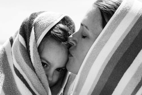 Monochrome Photo of Mom Kissing Her Child on the Forehead