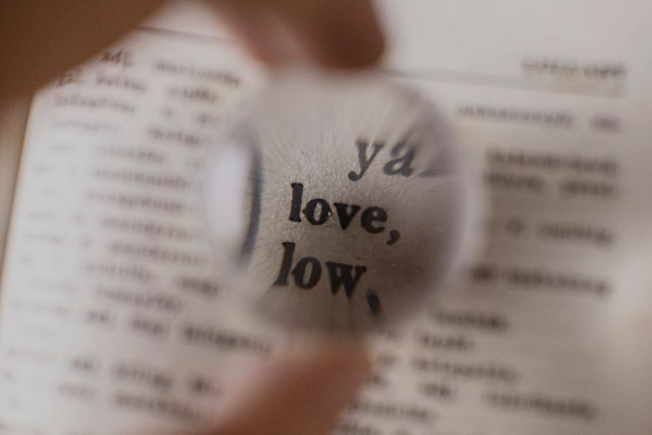 Close-up of a magnifying glass focusing on the word 'love' in a dictionary.
