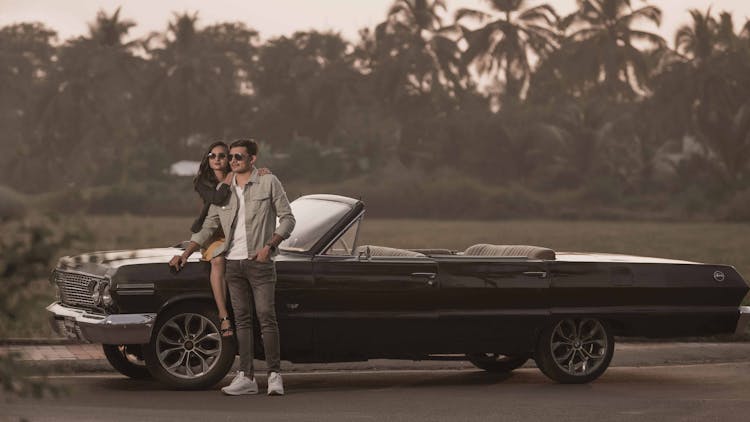 A Couple Posing On A Convertible Car