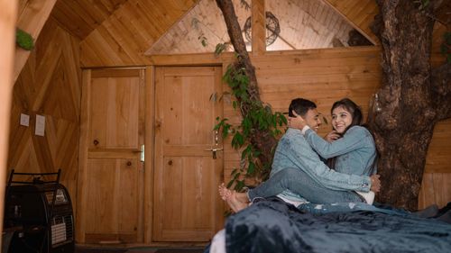 Free A young couple in denim jackets enjoying a warm moment indoors in a rustic wooden cabin. Stock Photo