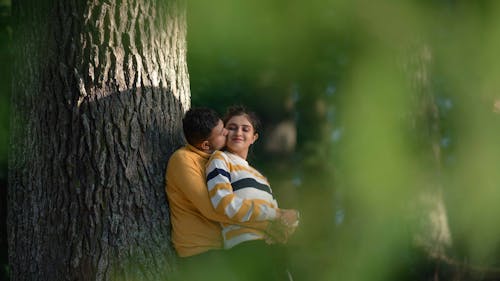 Man in Yellow Long Sleeve Shirt Leaning on Tree