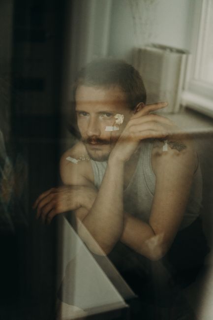 Portrait of a pensive man through a blurred window, reflecting introspection.