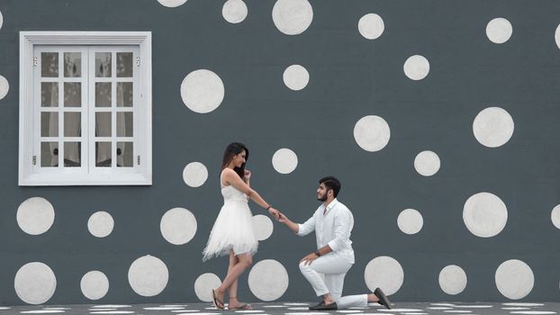 Woman in White Long Sleeve Shirt and White Pants Standing on White and Blue Polka Dot