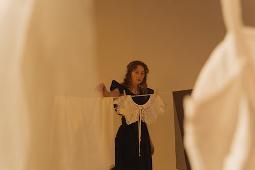 A Woman in Black Dress Standing in Front of a Clothesline