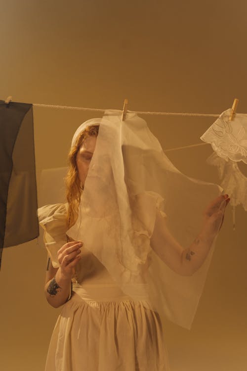 A Woman Holding the Fabric Hanging on the Clothesline