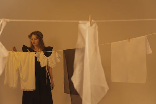 Woman in Black Dress Looking at the Clothes on the Clothesline