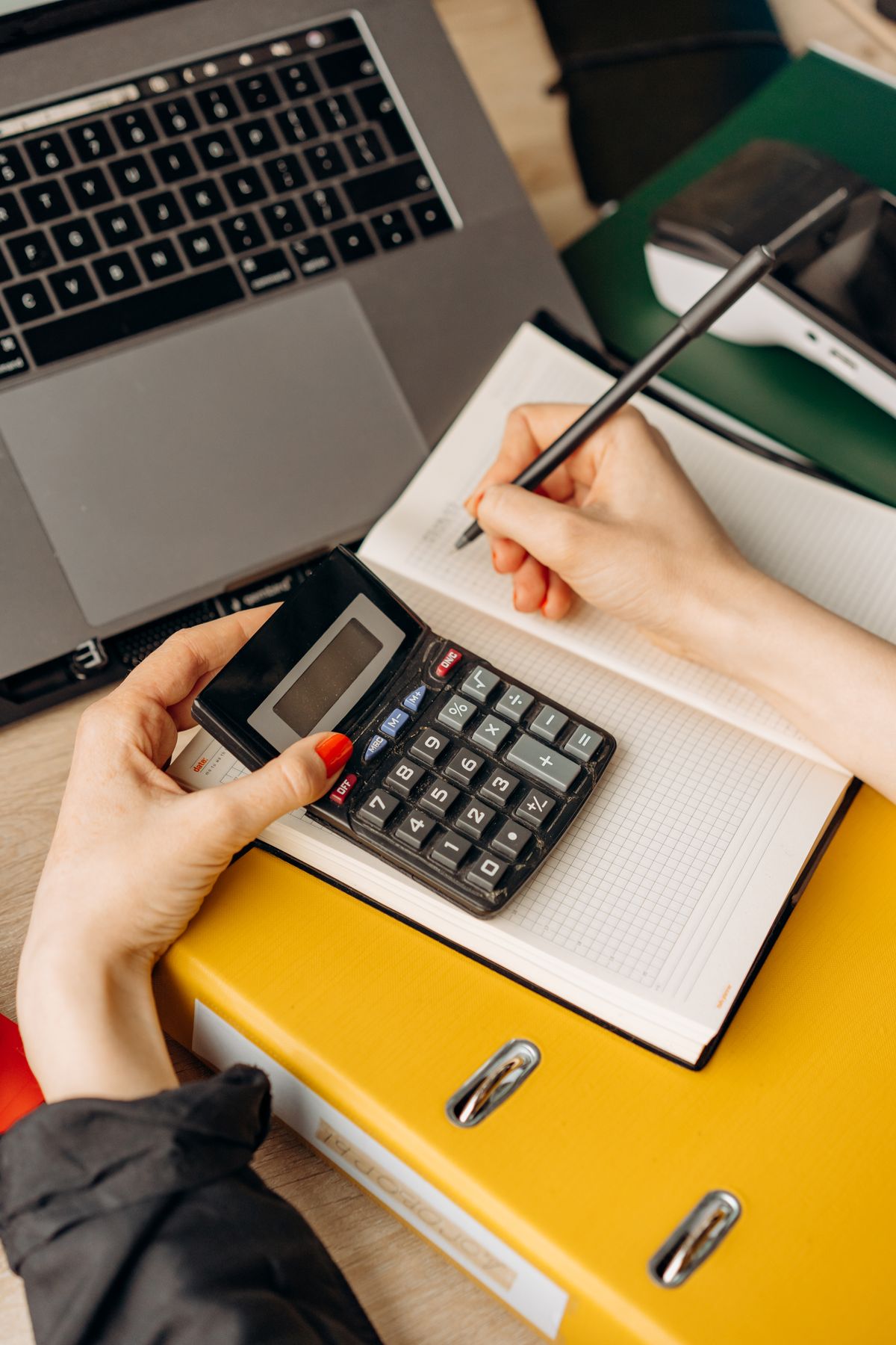 Person using a calculator and notebook at a workspace