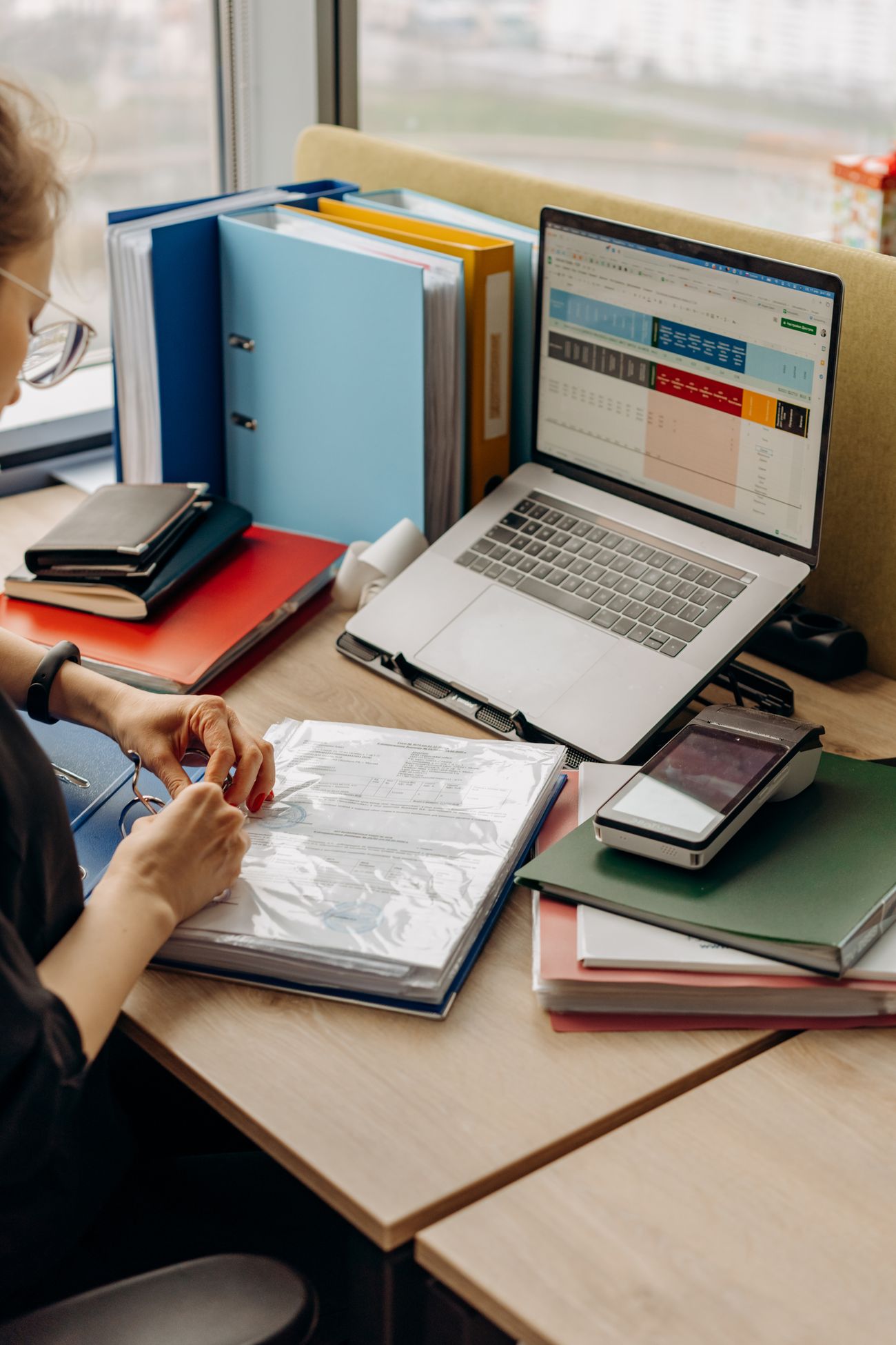 Person reviewing accounting documents with a laptop