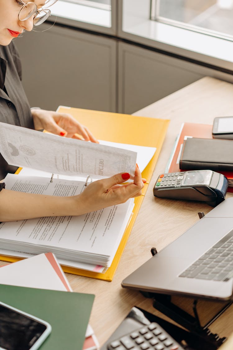 Woman Flipping Pages On A Wooden Table