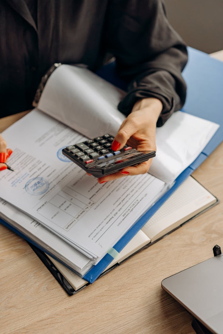 Person Holding Calculator Checking On Documents